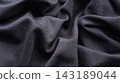 A close-up of a soft wrinkled black jersey fabric. 143189044