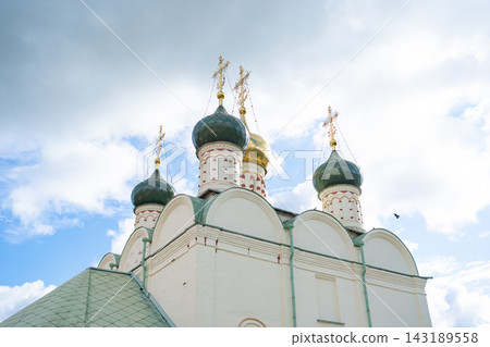 serene view of an orthodox church standing tall with crosses, set against a sky filled with clouds, featuring brick and metal construction, with white and green accents, captured from a low. serene view of an orthodox church standing tall with crosses, set against a sky filled with clouds, featuring brick and metal construction, with white and green accents, captured from a low. 143189558