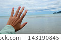 Open Human Hand Reaching Out Toward Ocean and Sky Background 143190845