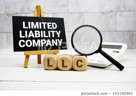 LLC Limited Liability Company text with calculator magnifying glass and on wooden background LLC Limited Liability Company text with calculator magnifying glass and on wooden background 143190992