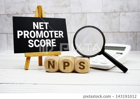 NPS Net Promoter Score text with calculator magnifying glass and on wooden background 143191012