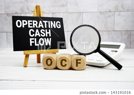 OCF Operating Cash Flow text with calculator magnifying glass and on wooden background OCF Operating Cash Flow text with calculator magnifying glass and on wooden background 143191016
