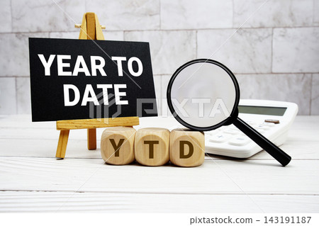 YTD Year To Date text with calculator magnifying glass and on wooden background YTD Year To Date text with calculator magnifying glass and on wooden background 143191187