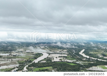 Mist blankets an aerial view of the swollen Khlong Yang canal overflowing into rural rice fields in Uthai Thani. Mist blankets an aerial view of the swollen Khlong Yang canal overflowing into rural rice fields in Uthai Thani. 143191655