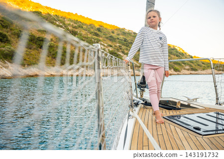 Young girl walking barefoot on sailing yacht deck near Croatian coast. Sailing vacation gives children freedom, confidence and experience of life at sea Young girl walking barefoot on sailing yacht deck near Croatian coast. Sailing vacation gives children freedom, confidence and experience of life at sea 143191732