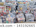 Compressed aluminum cans form dense metal bales stacked at recycling facility. Industrial waste processing scene shows scrap recovery, sorting, reuse, sustainability, circular economy and resources 143192665