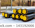 Insulated district heating pipes stacked urban construction site winter covered snow installation public utility network. Energy infrastructure pipeline thermal insulation municipal heating supply 143192666