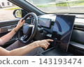 Woman operating the infotainment screen in her vehicle. 143193474