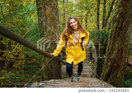 Active woman with backpack enjoys hiking on wooden stairs in autumn forest. Active woman with backpack enjoys hiking on wooden stairs in autumn forest. 143193883