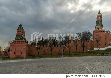 Moscow Kremlin Red Brick Wall and Towers Under Moody Cloudy Sky Over Empty Cobblestone Square 143194863