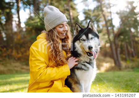 Young woman walks with her husky on lawn in the park. Happy female posing outdoors with her dog. Young woman walks with her husky on lawn in the park. Happy female posing outdoors with her dog. 143195207