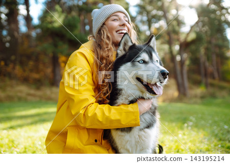 Young woman walks with her husky on lawn in the park. Happy female posing outdoors with her dog. Young woman walks with her husky on lawn in the park. Happy female posing outdoors with her dog. 143195214
