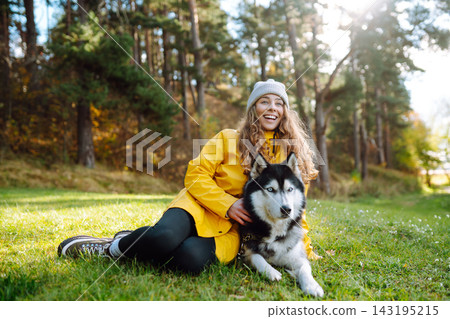 Young woman walks with her husky on lawn in the park. Happy female posing outdoors with her dog. Young woman walks with her husky on lawn in the park. Happy female posing outdoors with her dog. 143195215