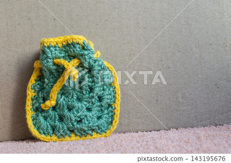 Crocheted bag in green and yellow yarn on a gray background Crocheted bag in green and yellow yarn on a gray background 143195676