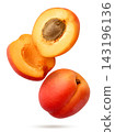 A ripe apricot and two halves flying close-up on a white background. Isolated 143196136