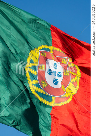 Close up of big Portuguese flag with coat of arms waving against blue sky 143196229