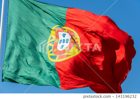 Close up of large Portuguese flag waving in the wind against clear blue sky Close up of large Portuguese flag waving in the wind against clear blue sky 143196232