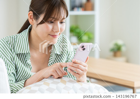 在客廳裡使用智能手機的年輕女子 143196767