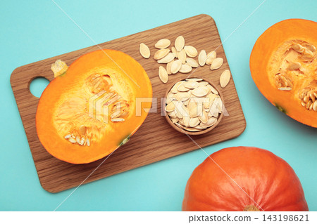 Sliced Hokkaido pumpkin with seeds on bowl on blue background. Sliced Hokkaido pumpkin with seeds on bowl on blue background. 143198621