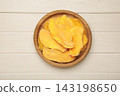 Slices of dried mango on wooden plate on light wooden background. 143198650