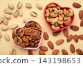 Mixed nuts on a heart-shaped plate on beige background. Almonds, pistachio, walnuts, cashew, hazelnut. Space for text 143198653