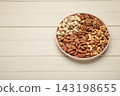 Mix of various nuts on plate on light background. Pistachios, cashews, walnuts, hazelnuts, peanuts. Space for text 143198655