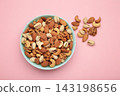 Mix of various nuts in mint bowl on pink background. Pistachios, cashews, walnuts, hazelnuts, peanuts. 143198656