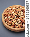 Mix of various nuts on plate on dark background. Pistachios, cashews, walnuts, hazelnuts, peanuts. 143198657