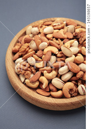 Mix of various nuts on plate on dark background. Pistachios, cashews, walnuts, hazelnuts, peanuts. Mix of various nuts on plate on dark background. Pistachios, cashews, walnuts, hazelnuts, peanuts. 143198657