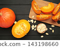 Sliced Hokkaido pumpkin with seeds on bowl on black wooden background. 143198660