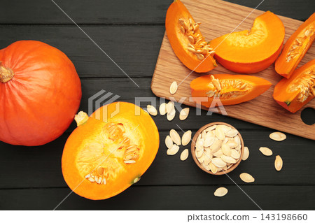 Sliced Hokkaido pumpkin with seeds on bowl on black wooden background. Sliced Hokkaido pumpkin with seeds on bowl on black wooden background. 143198660