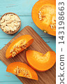 Sliced Hokkaido pumpkin with seeds on bowl on blue wooden background. Vertical photo 143198663