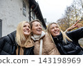 Cheerful friends laugh together on autumn city walk, sharing hugs and joyful travel moments. Candid group portrait captures friendship, reunion, happiness, leisure and weekend adventure outdoors 143198969