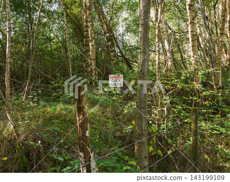 Warning Sign on Metal Wire Mesh Fence in Green Forest 143199109