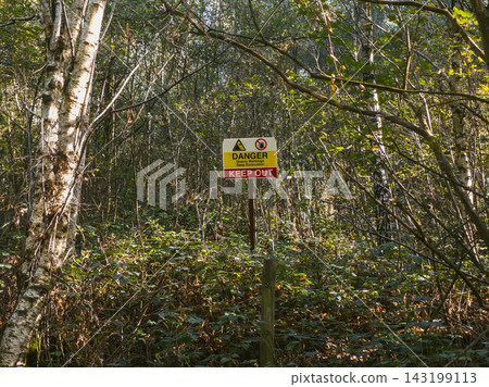 Warning Sign on Metal Wire Mesh Fence in Green Forest 143199113