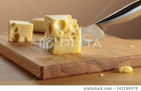 Cheese and knife on a wooden cutting board. Cheese and knife on a wooden cutting board. 143199378