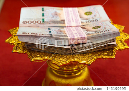 Four bundled thousand Thai Baht stacks on golden tray feature straps translating to Quantity 100 notes and Bank of Thailand Note Printing Works. Four bundled thousand Thai Baht stacks on golden tray feature straps translating to Quantity 100 notes and Bank of Thailand Note Printing Works. 143199695
