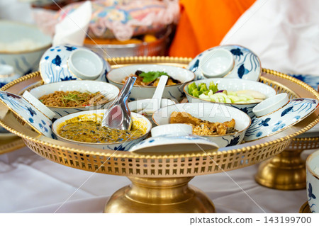 Traditional Thai food in blue and white porcelain bowls on ornate golden trays is offered to monks during a religious ceremony. Traditional Thai food in blue and white porcelain bowls on ornate golden trays is offered to monks during a religious ceremony. 143199700