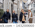 Cheerful friends laugh together on autumn city walk, sharing hugs and joyful travel moments. Candid group portrait captures friendship, reunion, happiness, leisure and weekend adventure outdoors 143200660