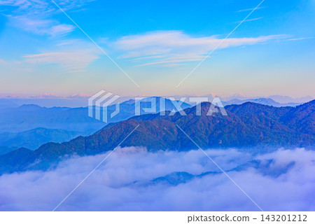 A view captured with a medium telephoto lens from the summit of Mt. Tōnodake in the Tanzawa Mountains in early summer, showing the snow-capped peaks of the Southern Alps shining beautifully in the morning sun beyond the Tanzawa mountain range. 143201212