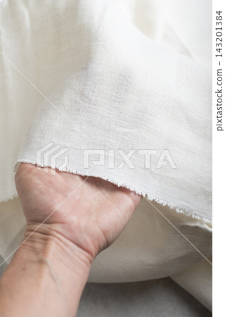 Hand Holding Off White Linen Fabric Edge Hand Holding Off White Linen Fabric Edge 143201384