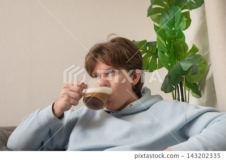 Young man relaxing with cup of coffee. Leisure Activities At Home Young man relaxing with cup of coffee. Leisure Activities At Home 143202335