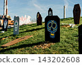Painted skull markers stand among grass and autumn leaves. Concept of Halloween, mortality, folklore, decoration, celebration, fantasy and tradition. 143202608