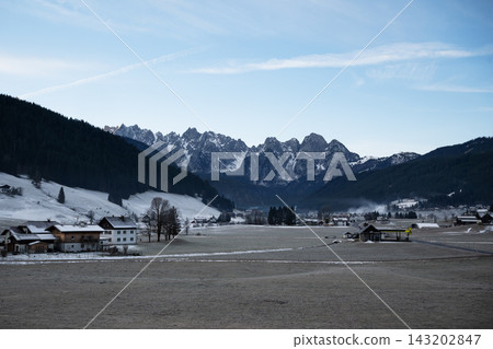 Wide landscape shot of Gosau village surrounded by snow covered Gosaukamm alpine peaks and pine forest in winter. Alpine village in Salzkammergut, Austria. Wide landscape shot of Gosau village surrounded by snow covered Gosaukamm alpine peaks and pine forest in winter. Alpine village in Salzkammergut, Austria. 143202847