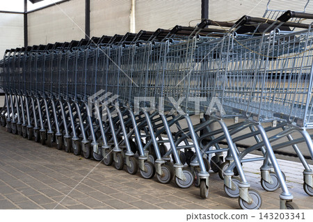 Row of Metal Shopping Carts Outside Supermarket Store for Retail Shopping and Consumerism Concept Row of Metal Shopping Carts Outside Supermarket Store for Retail Shopping and Consumerism Concept 143203341
