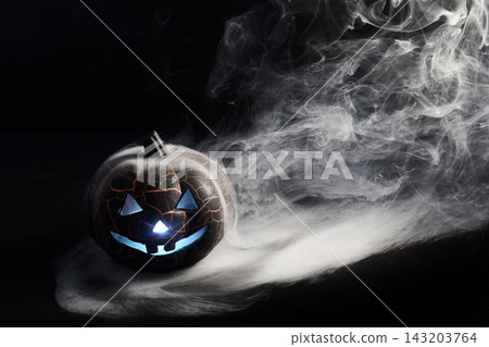 Halloween pumpkin glowing with blue light and smoke Halloween pumpkin glowing with blue light and smoke 143203764