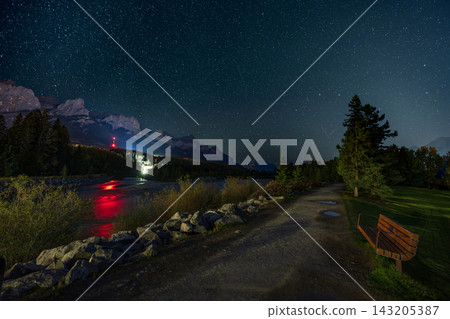 The starry sky stretching across the Yumikawa River and walking path, and the Canadian Rockies. Canmore, Alberta, Canada. The starry sky stretching across the Yumikawa River and walking path, and the Canadian Rockies. Canmore, Alberta, Canada. 143205387