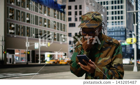 Delighted army soldier outdoors gasping after receiving good news on phone, returning home and feeling happy. Thrilled woman on city street surprised by message on smartphone. Delighted army soldier outdoors gasping after receiving good news on phone, returning home and feeling happy. Thrilled woman on city street surprised by message on smartphone. 143205487