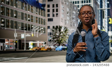 Presenting information on mic, field reporter girl downtown, on city street speaking towards camera. Black journalist presenting breaking news reportage with updates, live commentary. Presenting information on mic, field reporter girl downtown, on city street speaking towards camera. Black journalist presenting breaking news reportage with updates, live commentary. 143205488