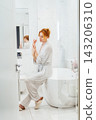 Relaxed middle aged woman Applying Hand Cream in bathroom during morning routine, Dry Skin Remedy. Skin hydrating. Cosmetic spa procedures. Beauty self-care at home. Home Beauty treatment. Vertical. 143206310